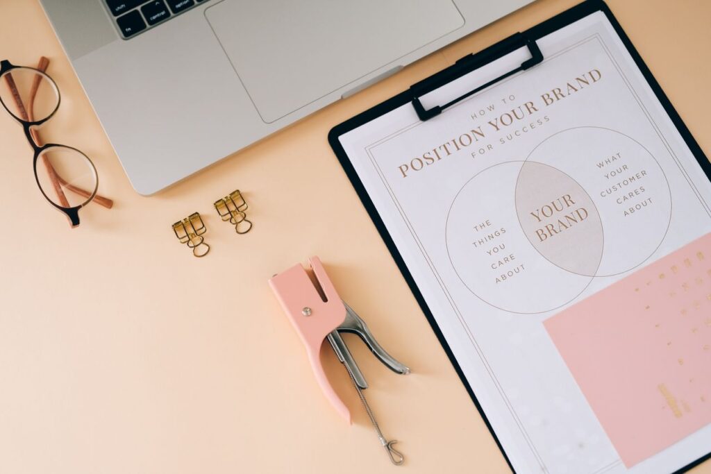 A flat lay composition featuring office essentials and a branding strategy clipboard on a modern workspace.